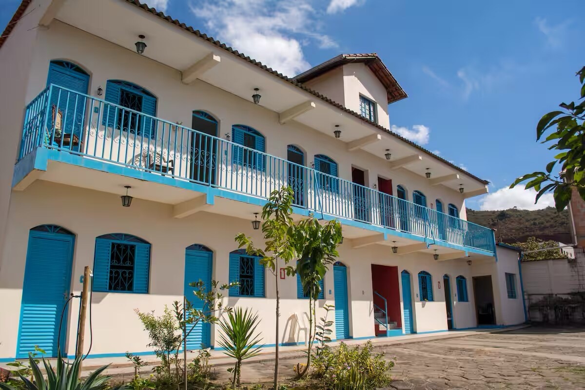 Fachada da Pousada da Serra, sobrado branco de dois pavimentos com varandas e esquadrias azuis, em Barão de Cocais