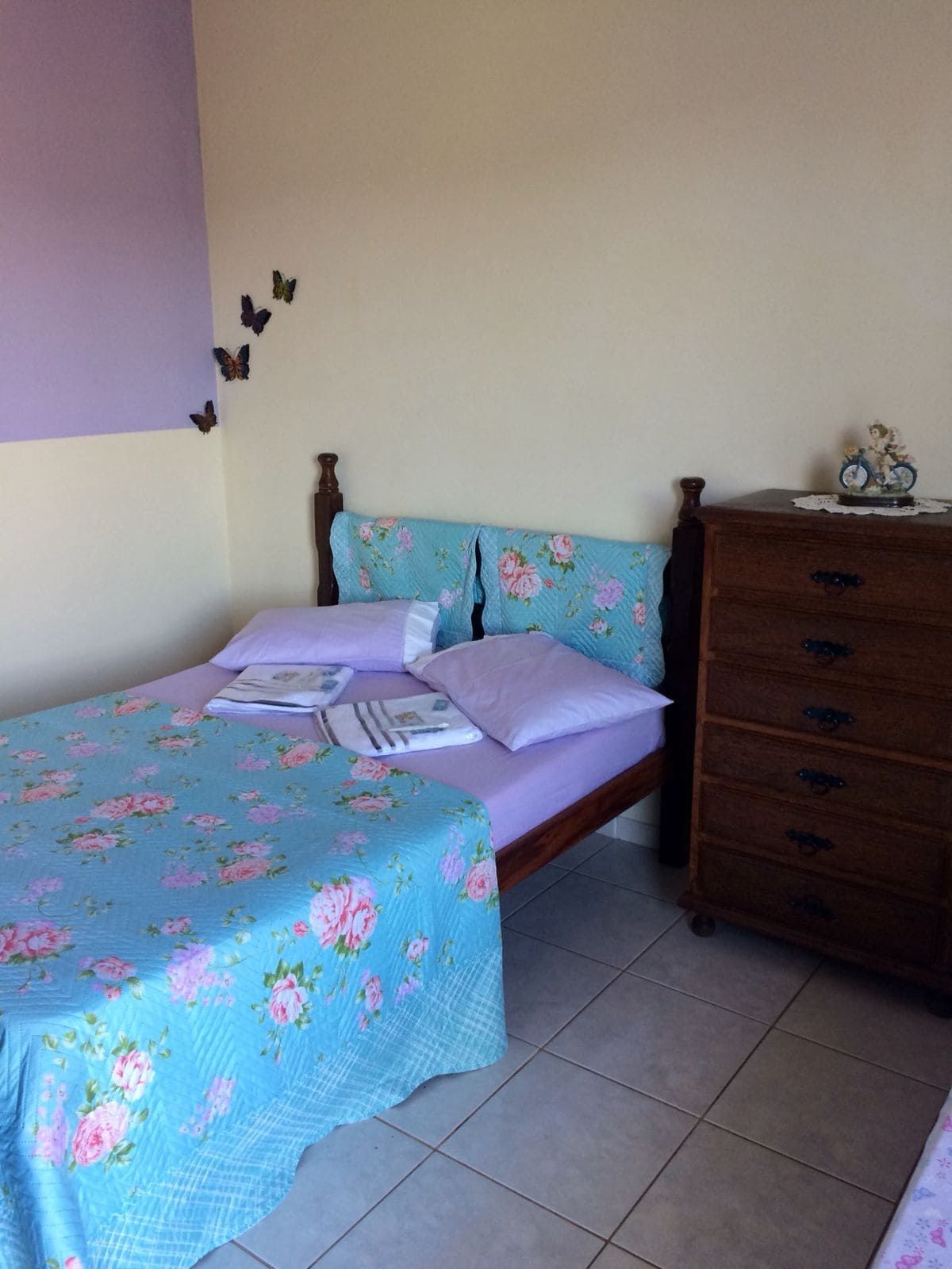 Quarto com cama de casal e parede lilás