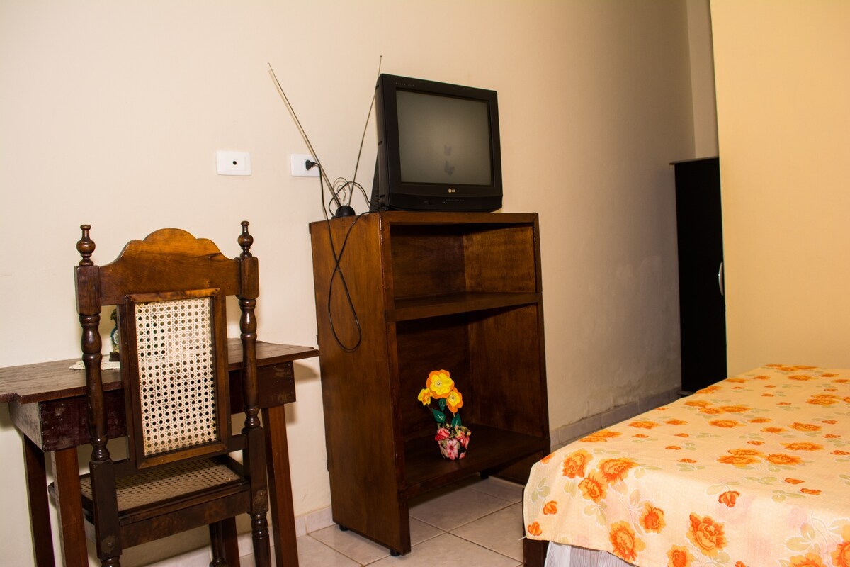 Quarto com cama de solteiro e escrivaninha de madeira