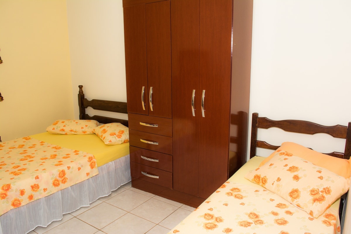 Quarto com duas camas de solteiro e guarda-roupa de madeira